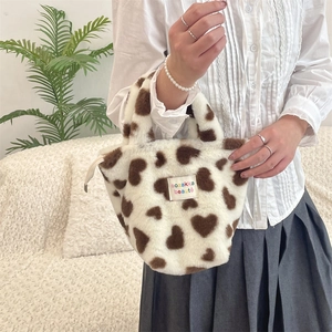 Close-up of soft plush handbag featuring heart patterns and fabric brand label