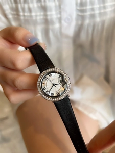 Close-up of women's watch featuring a crystal bezel and black leather strap