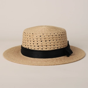 Detail of hand-woven boater hat with a chic black ribbon bow on premium raffia straw