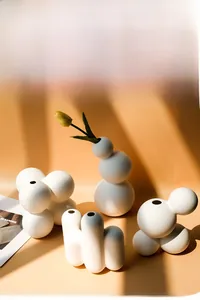 Artistic layout of matte white ceramic vases with stacked spherical and organic shapes