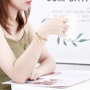 Bracelet à chaîne dorée avec pendentif cadenas porté par un mannequin en décor chic