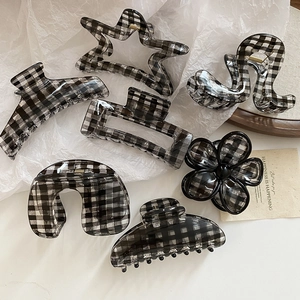 Macro view of 7-piece monochrome checkered acrylic hair claw clips on white paper