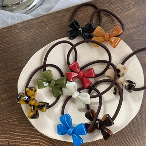 Detail of colorful acrylic bow hair ties in multiple shades on a neutral round mat