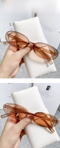 Close-up of tea-colored cat-eye sunglasses with a textured white leather case