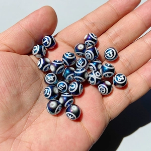 Rainbow black glass beads with zodiac constellations held in palm for DIY jewelry