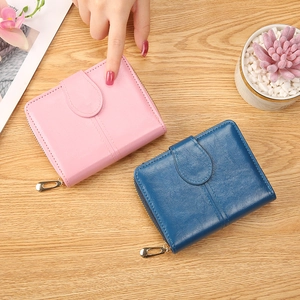 Short women's faux leather folding wallets in pink and blue on a wooden table