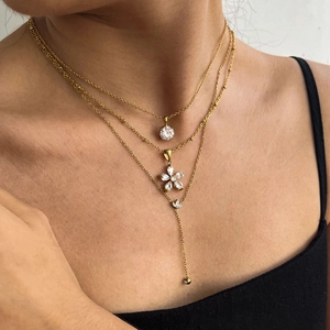 Close-up of triple-layered gold zircon necklace featuring floral and Y-shaped chain details