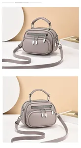 Detail of grey lychee textured leather bag with three silver zippers and top handle