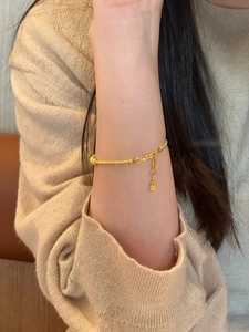 Detailed view of a gold gourd charm bracelet with intricate wire-wrap metal texture