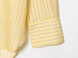 Vista dettagliata del tessuto della camicia a righe gialle e cuciture del polsino