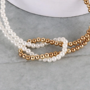 Detailed close-up of double-layer gold metal beads and white faux pearls on a necklace