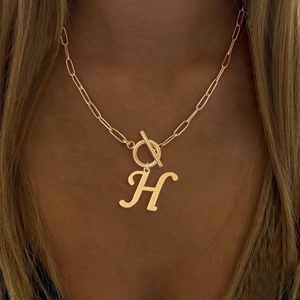 Close-up of golden letter H pendant necklace with paperclip chain and OT clasp
