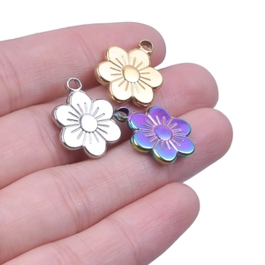 Close-up of three floral pendants in gold, silver, and rainbow steel for DIY jewelry