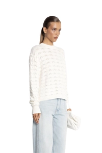 Detail of white hollow-out knit sweater showing delicate patterns and long sleeves