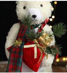 Close-up of a white plush Christmas bear with a red scarf and a velvet gift bag