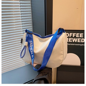 Detail of white half-moon canvas bag with blue fashion strap and rope zipper pull