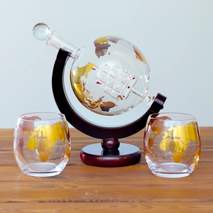 Detail of globe whiskey decanter set with sailboat glass model and gold world map