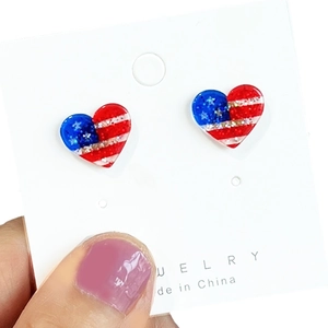Detail shot of heart-shaped American flag earrings with glitter finish on display card
