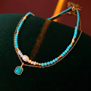 Dettaglio della collana a doppio strato placcata oro con turchese, perle e ciondolo quadro