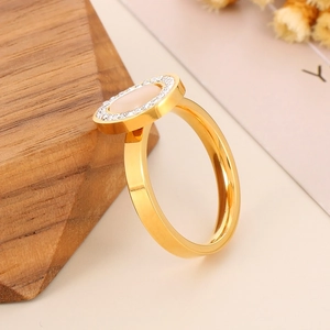 Detailed close-up of golden oval ring with white stone and sparkling zircon border