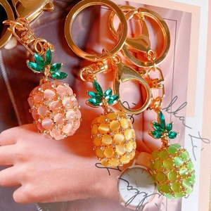 Detail of colorful opal stone pineapple keychains with gold metal rings and green rhinestones