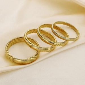 Gold ribbed snake chain stretch bracelets set on champagne silk fabric background