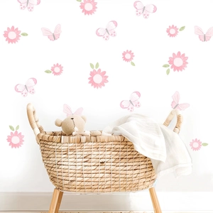 Pink floral and butterfly wall stickers in a cozy nursery room with a wooden basket
