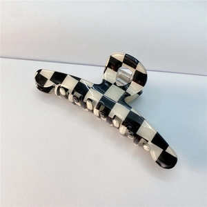 Detailed close-up of a large black and white checkered hair claw with polished finish