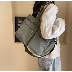 Detail of green corduroy shoulder bag showing side profile and zipper compartments
