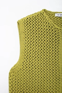 Detailed close-up of yellow knit vest neckline showing thick mesh texture and round neck