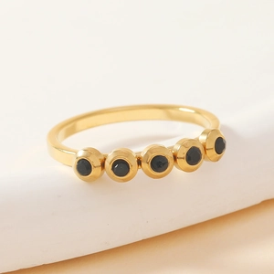 Detail of gold titanium steel ring featuring five bezel-set round black crystals