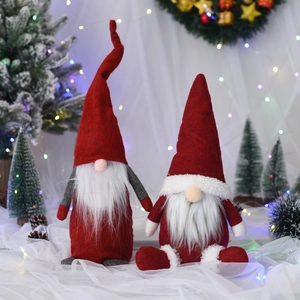 Detail von roten Weihnachtsgnomen aus Plüsch mit langen Bärten vor einem Schneebaum