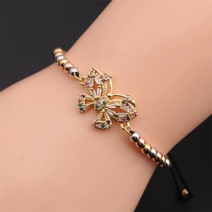 Dettaglio macro del bracciale a perle tricolore con ciondolo a farfalla d'oro e zirconi