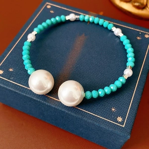 Détail de perles facettées turquoise et grandes perles blanches sur un coffret cadeau