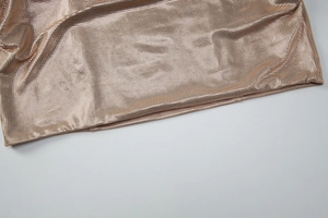 Vue macro détaillée du tissu en maille métallique dorée avec paillettes et plis brillants