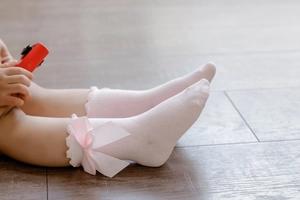 Detailed macro view of pink baby socks with lace trim and elegant satin bow accents