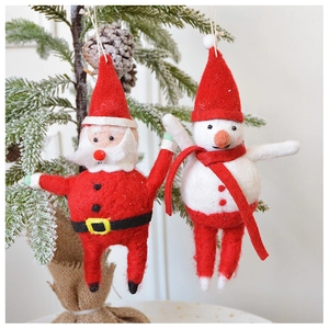 Close-up of wool felt Santa and snowman ornaments hanging on a snowy Christmas tree