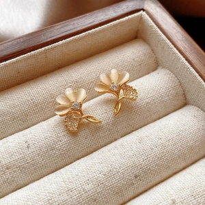 Detail of warm gold flower earrings with cat-eye stones and zircons in a wooden box