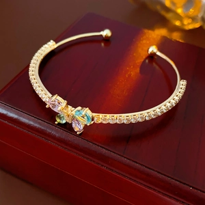 Eleganter goldener Armreif mit buntem Zirkonia-Schmetterling auf roter Box