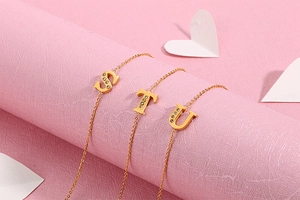 Detailed close-up of golden S T U letter pendants with sparkling rhinestones on chains