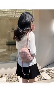 Lifestyle view of a dusty pink mini backpack with vintage monogram pattern and straps
