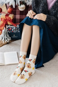 Detailed view of white cotton Christmas socks with festive reindeer and Santa hat patterns