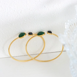 Vintage style gold plated cuff bracelets set with black and green stones on white background