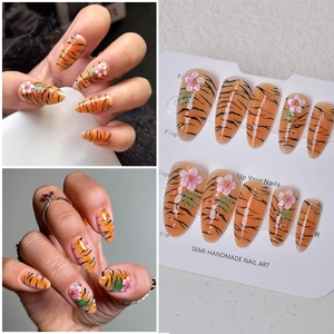 Detail of orange tiger stripe almond nails with 3D handmade floral art accents