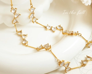 Macro detail of gold plated necklace featuring clear heart shaped zircon and sleek metal bars