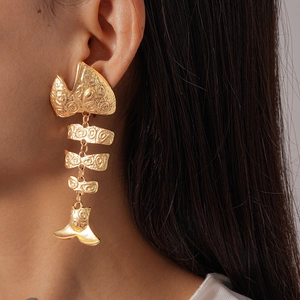 Close-up of golden fishbone earrings with spiral texture on a female model
