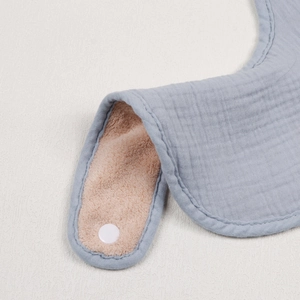 Detail of soft muslin gauze and absorbent terry backing on baby bib with snap closure