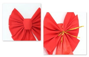 Detail of red festive bow showing matte fabric texture and gold twist tie fastener
