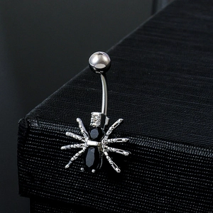 Silver spider belly button ring with black cubic zirconia on textured black background