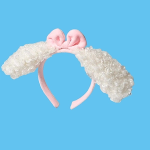 Detail of pink bow headband with large white fluffy faux fur lamb ears on blue background
